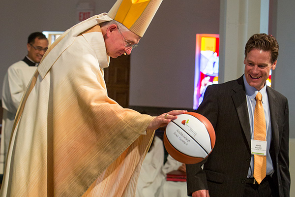 Kevin Baxter stands with Cardinal Roger Mahony as he dribbles a basketball