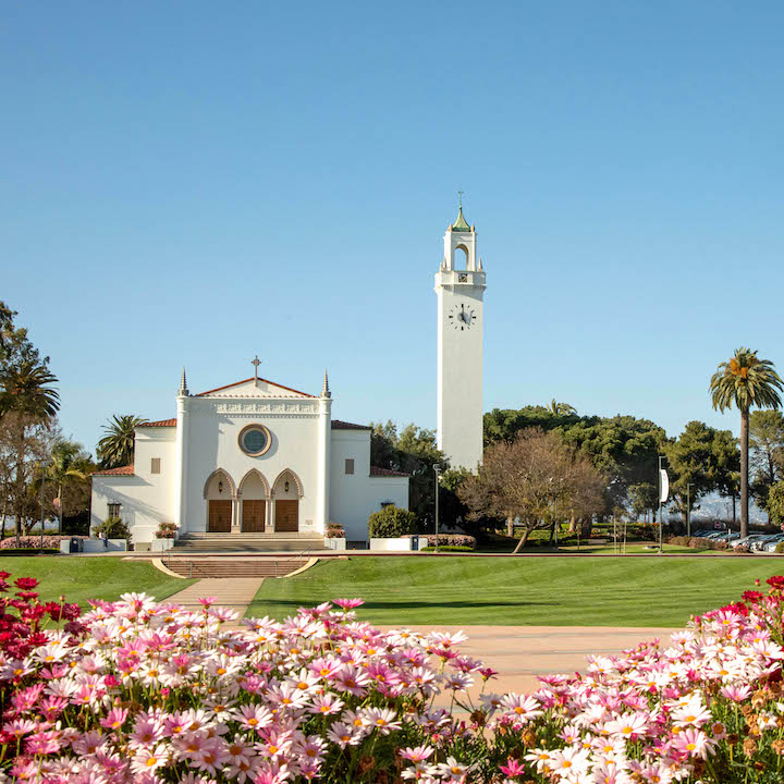 Sacred heart chapel with flowers in the foreground. Flowers are in bloom and are various shades of pink and white.